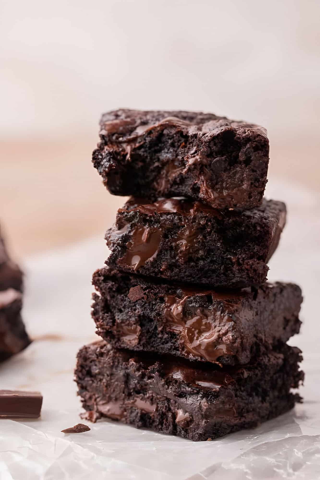 Three fudgy small batch brownies stacked to show the dense interior and melted chocolate pools.