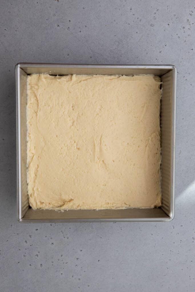First layer of sour cream cake batter spread evenly in an 8x8 pan for the Starbucks copycat coffee cake.