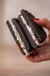 Hand holding Crumbl mallow oreo cookie sandwich cookie sliced in half