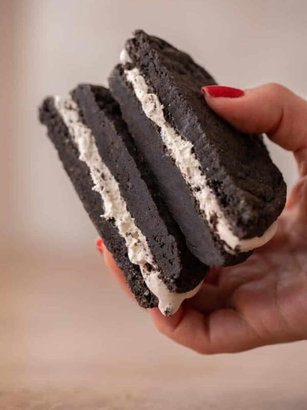 Hand holding Crumbl mallow oreo cookie sandwich cookie sliced in half