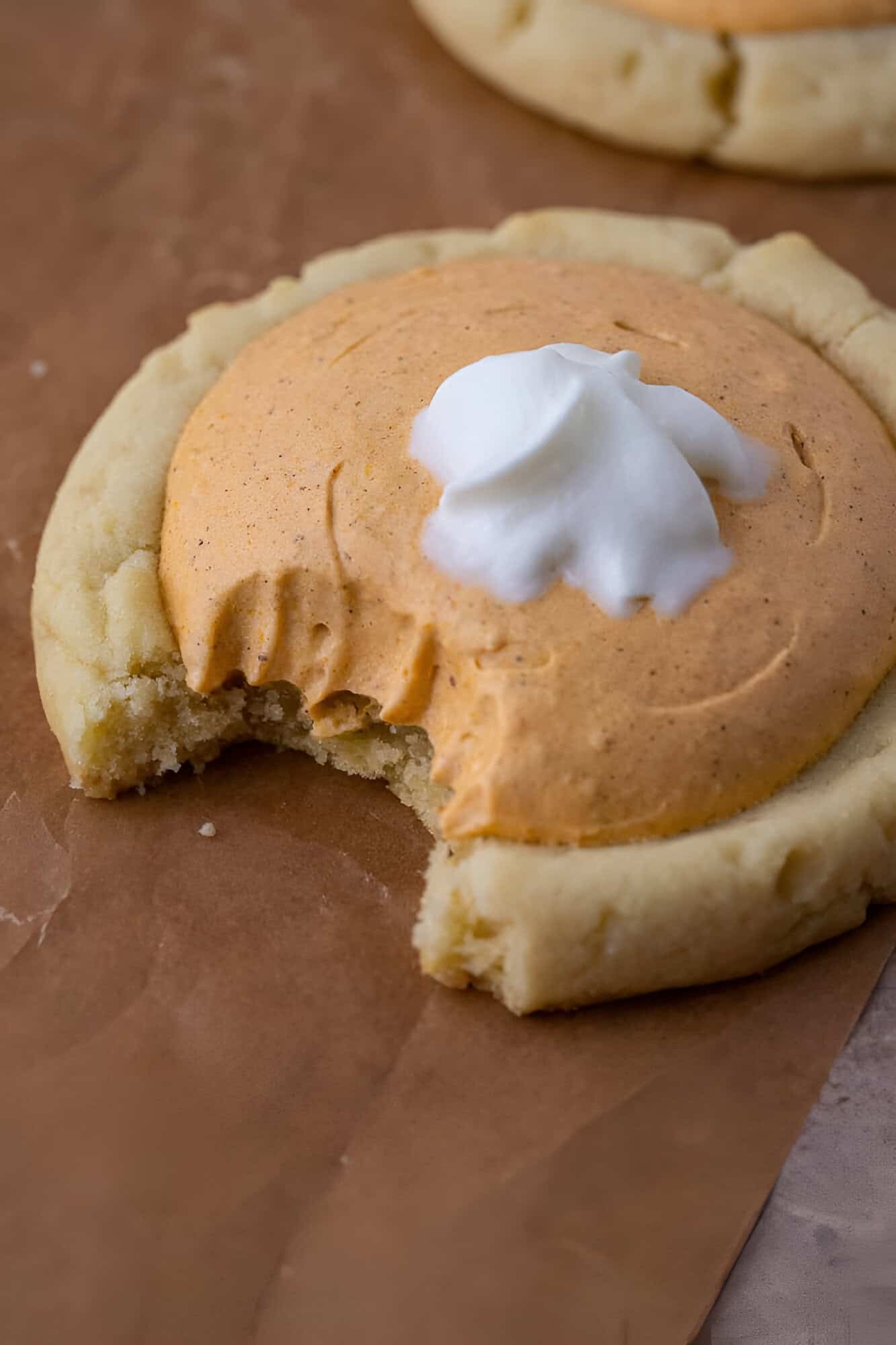 Crumbl pumpkin pie cookie with a bite taken out showing the whipped pumpkin mousse filling.