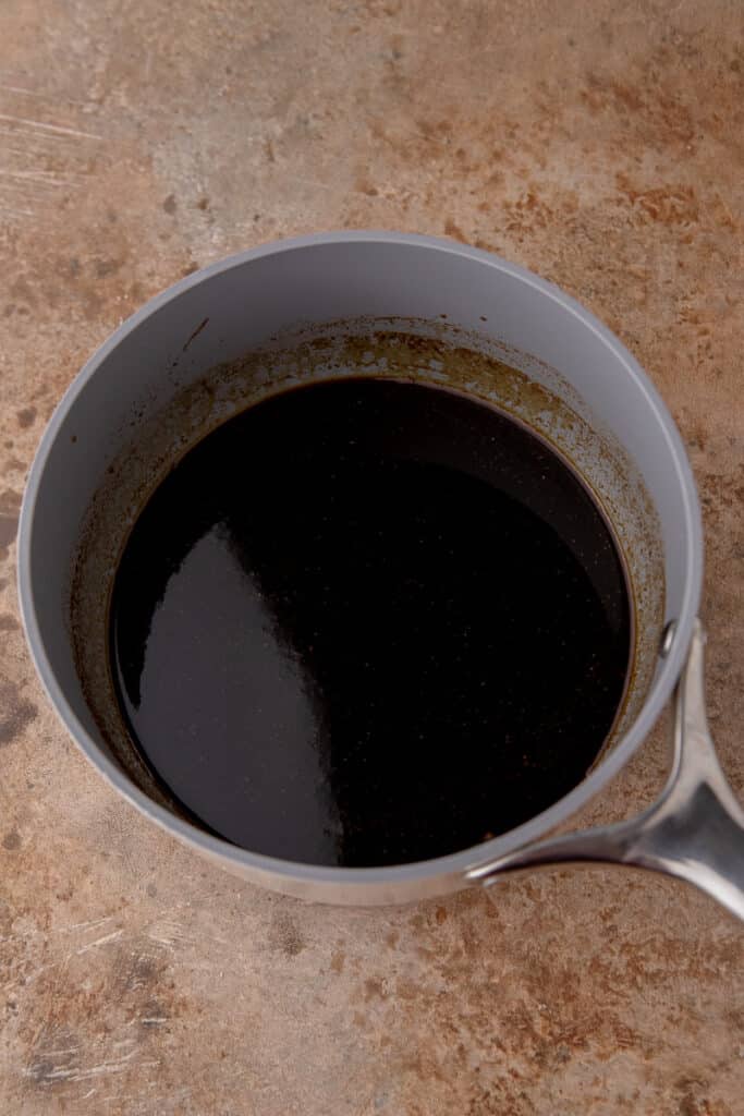 Dark, glossy syrup in a saucepan after simmering and thickening.