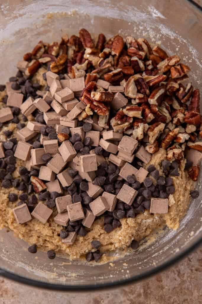 Adding pecans and chocolate chunks to cookie dough bowl
