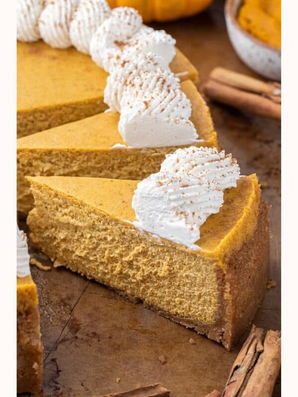 Sliced pumpkin cheesecake with swirls of whipped cream on top.