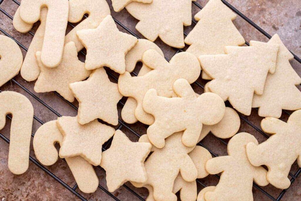 No spread cutout sugar cookies on a cooling rack shaped like stars, trees, and gingerbread men.