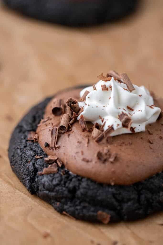 Crumbl French silk pie cookies on a baking sheet, topped with chocolate mousse, whipped cream, and chocolate shavings.