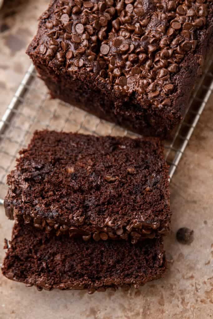 Double chocolate banana bread sliced on a wire cooling rack showing the rich dark crumb and melted mini chocolate chip topping