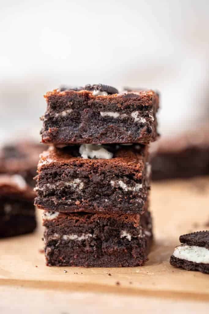 Stack of three fudgy Oreo brownies showing layers of Oreo cookies baked into the dense chocolate interior with Oreo pieces on top