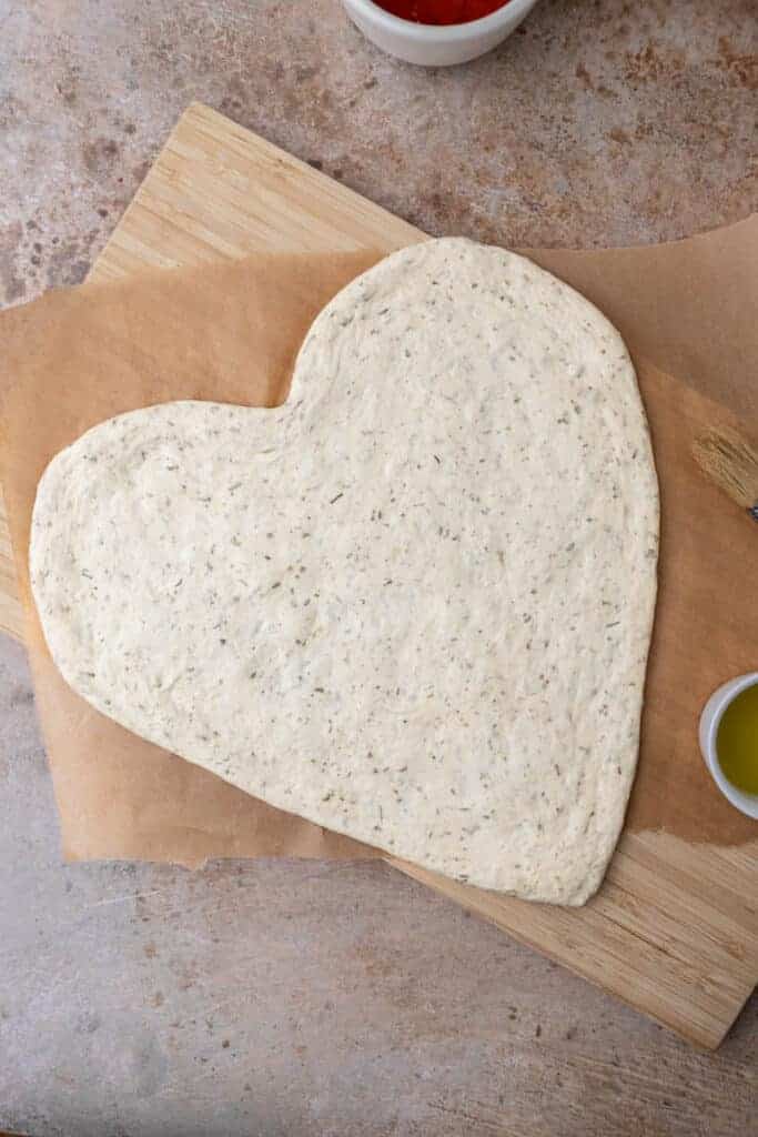 Final shaped pizza dough on a piece of parchment paper before adding toppings
