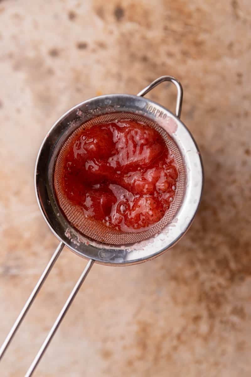 mashed strawberries in a sieve