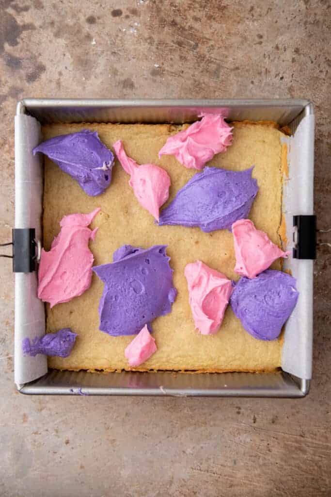 Pink and purple buttercream frosting dolloped onto baked cookie bars