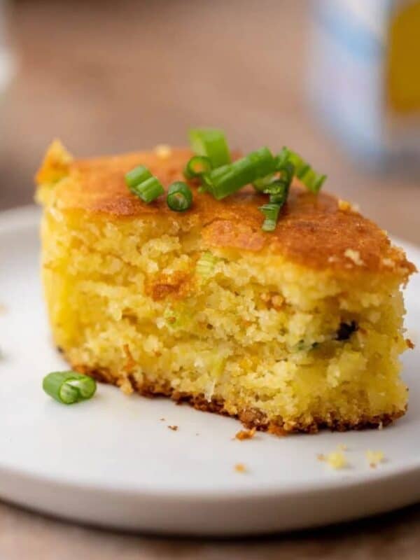 A square of cornbread with bites taken out of it, sitting on a small white plate.