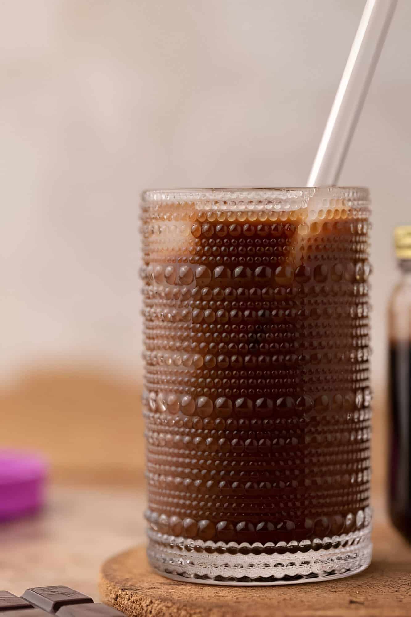 Tall glass of cold brew mocha with chocolate shaken through the coffee and milk poured over ice.
