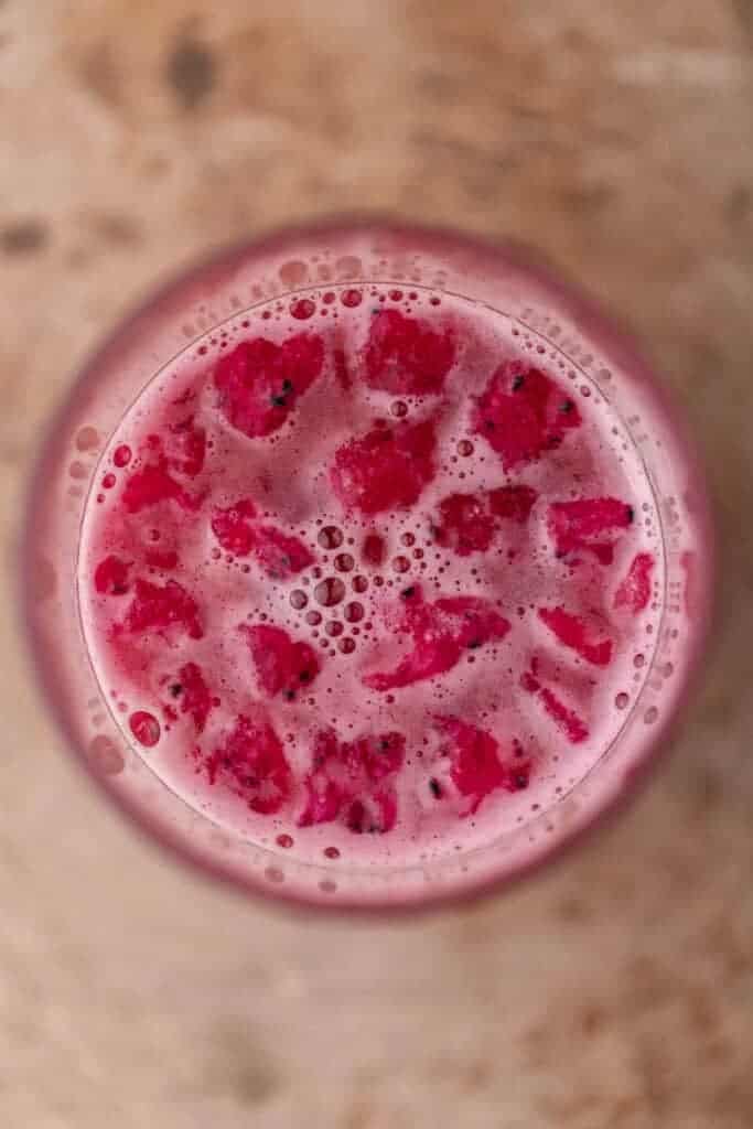 Top view of a pink iced drink with dragonfruit pieces