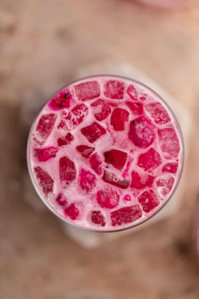 Overhead view of a homemade Starbucks pink drink with freeze dried dragonfruit pieces and coconut milk