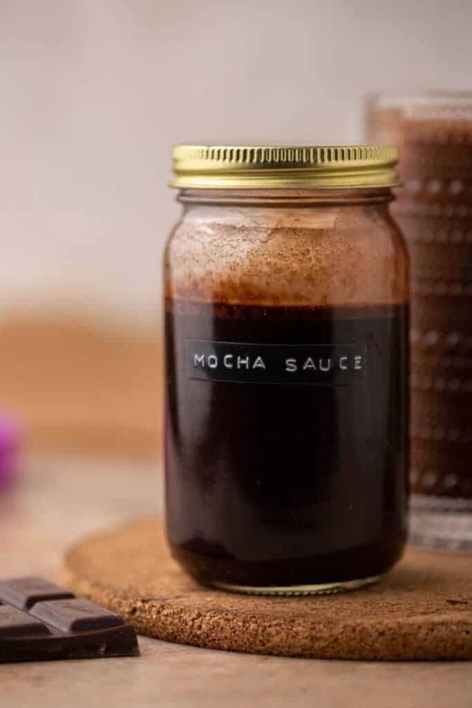 Homemade Starbucks mocha sauce stored in a glass jar with a gold lid for Starbucks copycat recipes