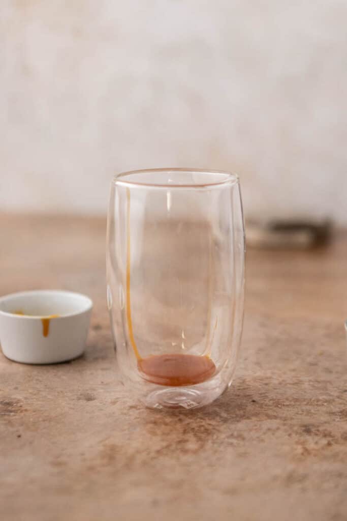 Caramel sauce added to the bottom of a tall glass before assembling the drink