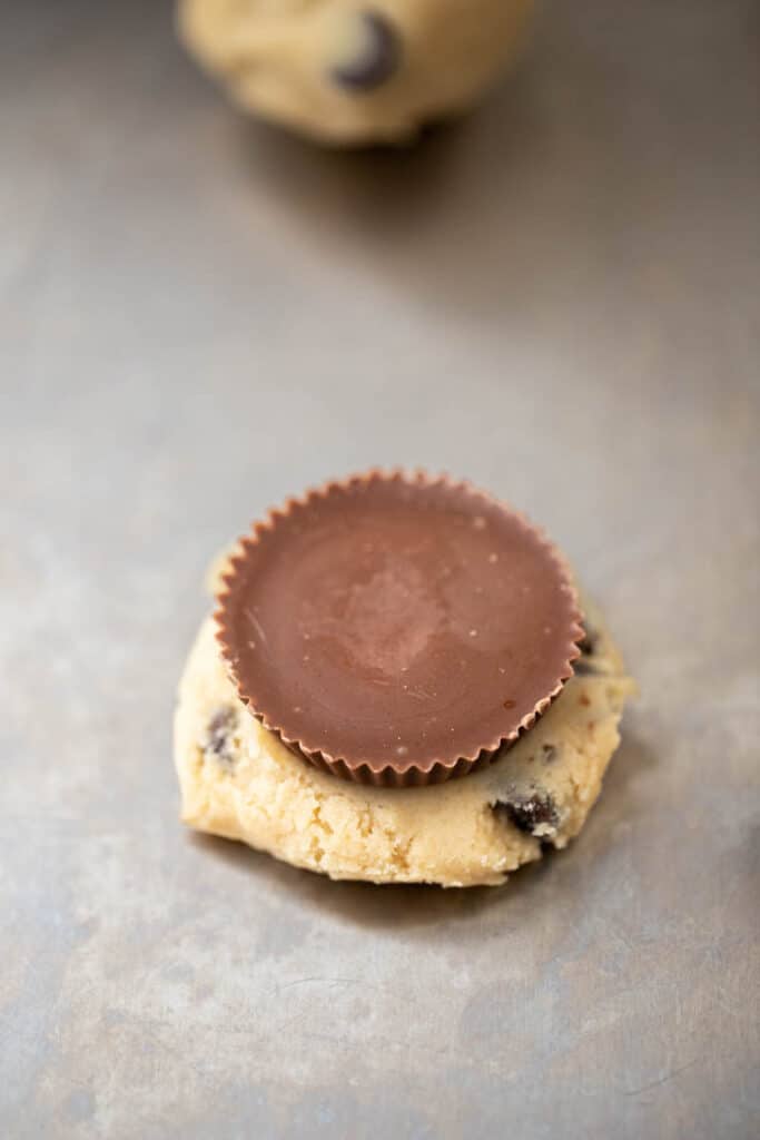 Reese’s peanut butter cup placed on flattened chocolate chip cookie dough before sealing