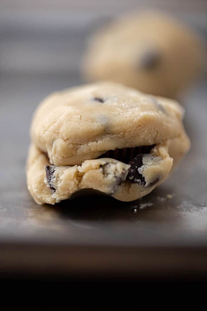 Unbaked Reese’s stuffed chocolate chip cookie dough sealed around peanut butter cup