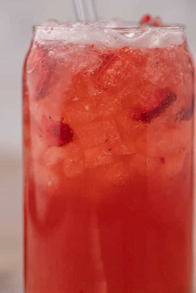 Starbucks copycat strawberry acai refresher with freeze dried strawberries and ice in a glass