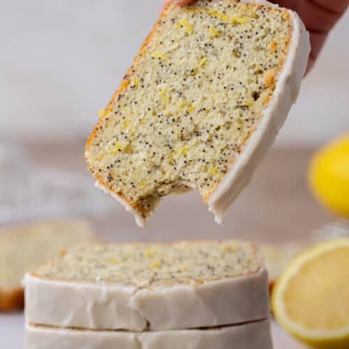 Hand holding slice of lemon poppy seed loaf cake