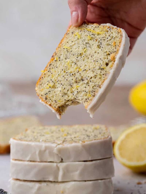 Hand holding slice of lemon poppy seed loaf cake