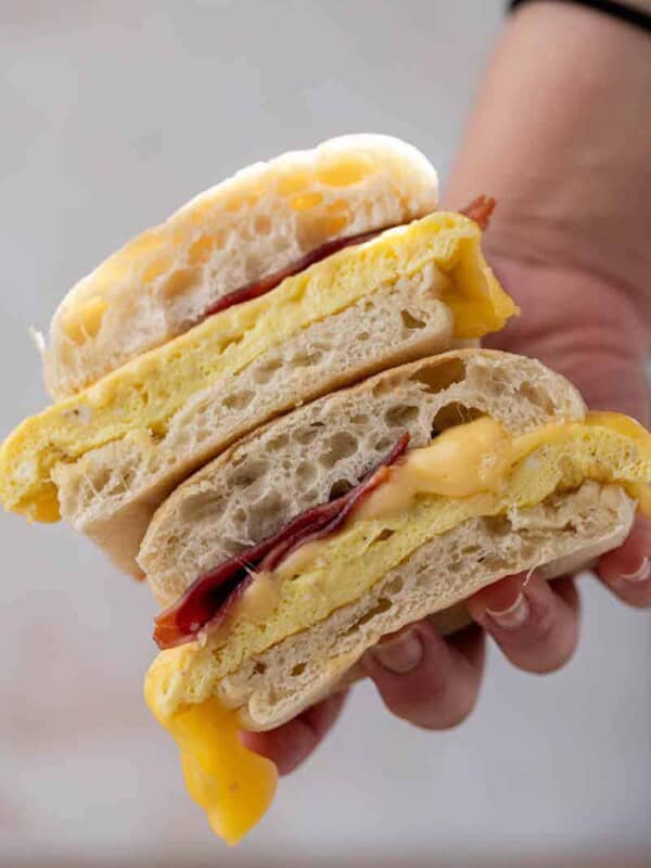 Hand holding Starbucks bacon egg and cheese sandwich
