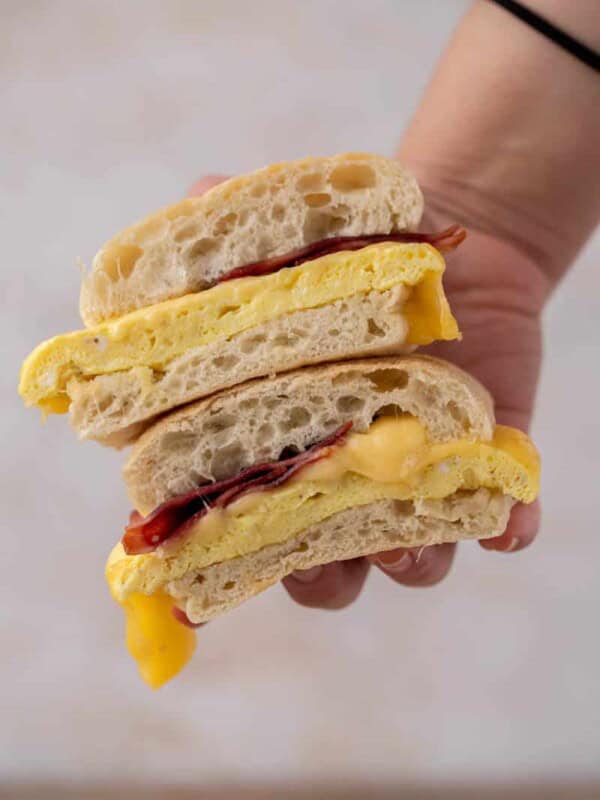 Hand holding bacon egg gouda sandwich from starbucks
