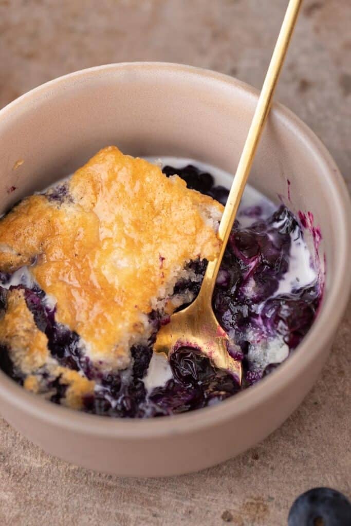 Closeup of blueberry cobbler in a bowl with sweet cream