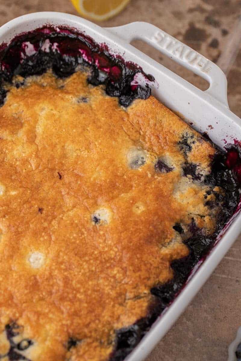 Golden baked blueberry cobbler in a white baking dish.