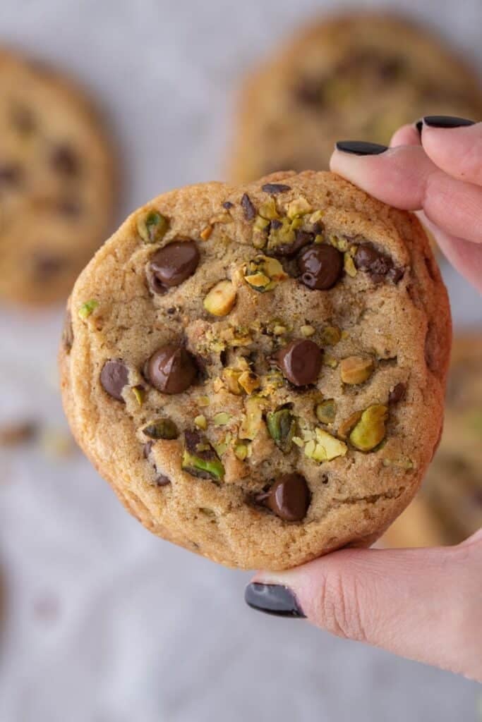 Hand holding Brown butter pistachio chocolate chip cookies