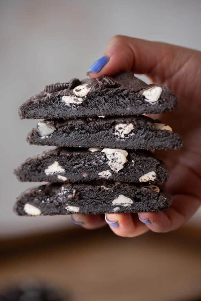 Hand holding stack of chocolate cookies and cream cookies