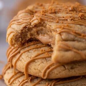 Stack of three Crumbl Biscoff lava cookies with cookie butter drizzle and crushed Speculoos on top.