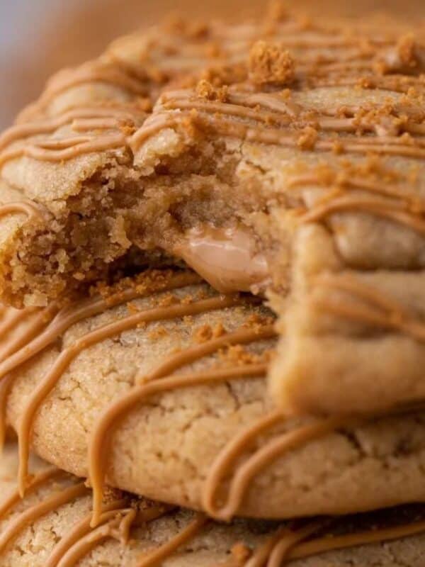 Stack of three Crumbl Biscoff lava cookies with cookie butter drizzle and crushed Speculoos on top.