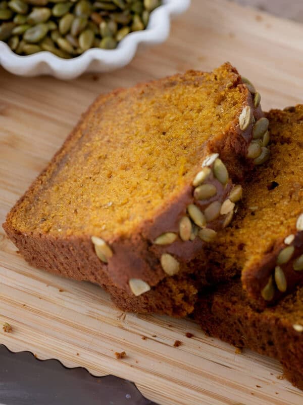 Thick slice of copycat Starbucks pumpkin bread topped with salted pepitas on a cooling rack.