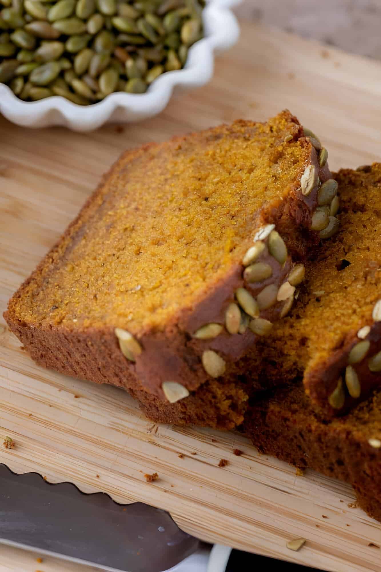 Thick slice of copycat Starbucks pumpkin bread topped with salted pepitas on a cooling rack.