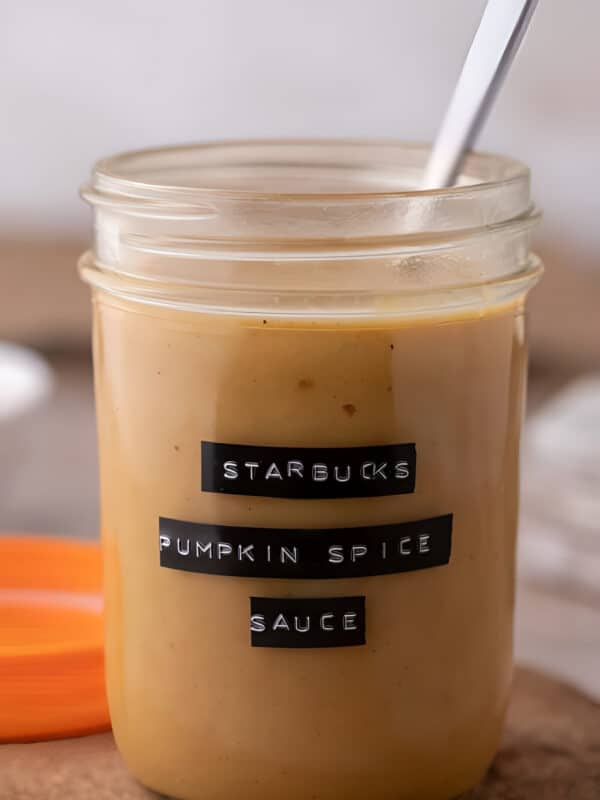 Homemade Starbucks pumpkin spice sauce filling a glass mason jar, thick and deep orange throughout.