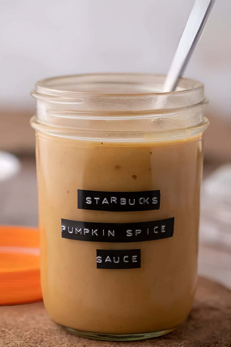 Homemade Starbucks pumpkin spice sauce filling a glass mason jar, thick and deep orange throughout.