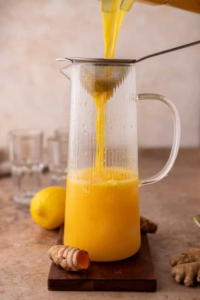 mixture being strained and poured into a pitcher