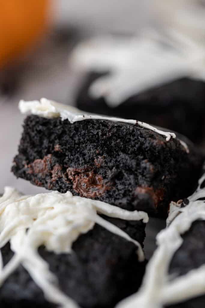 Midnight black cocoa brownies with white chocolate spider web drizzle showing the deep dark fudgy interior and intense chocolate color