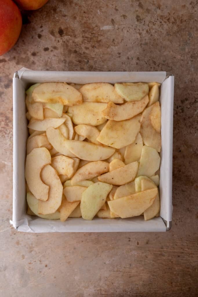 Sliced apples on top of shortcrust in a pan