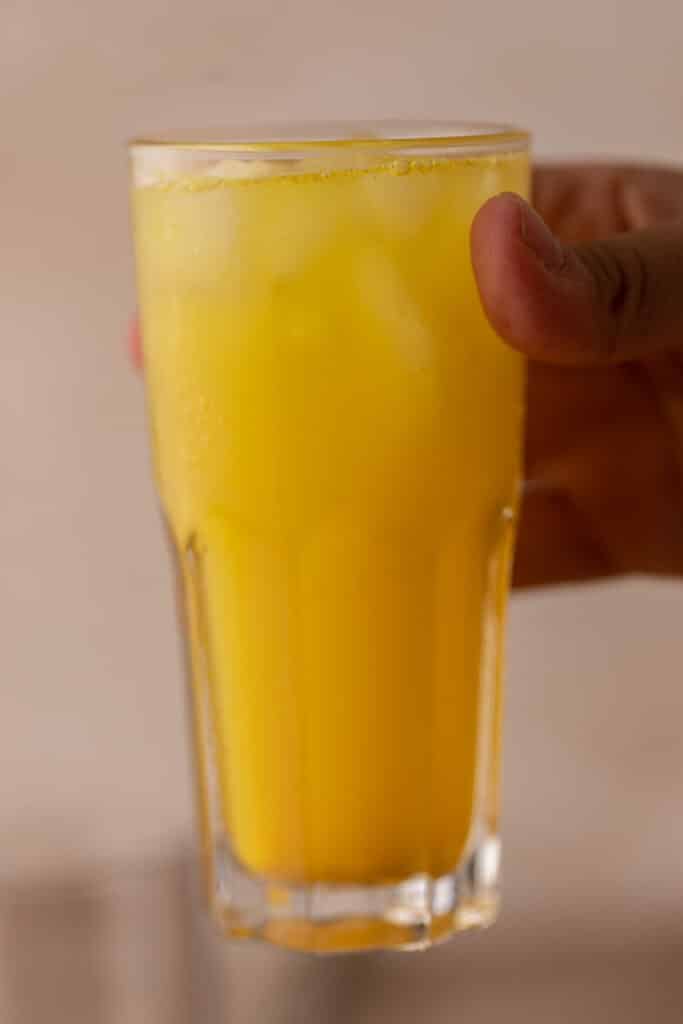 anti-inflammatory ginger turmeric tonic being held by a hand