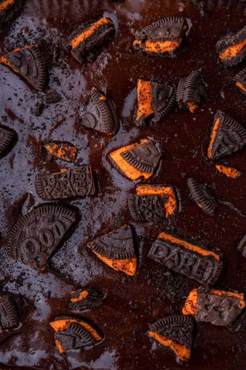 Close-up of the brownie batter topped with chopped Halloween Oreos, ready for the oven.