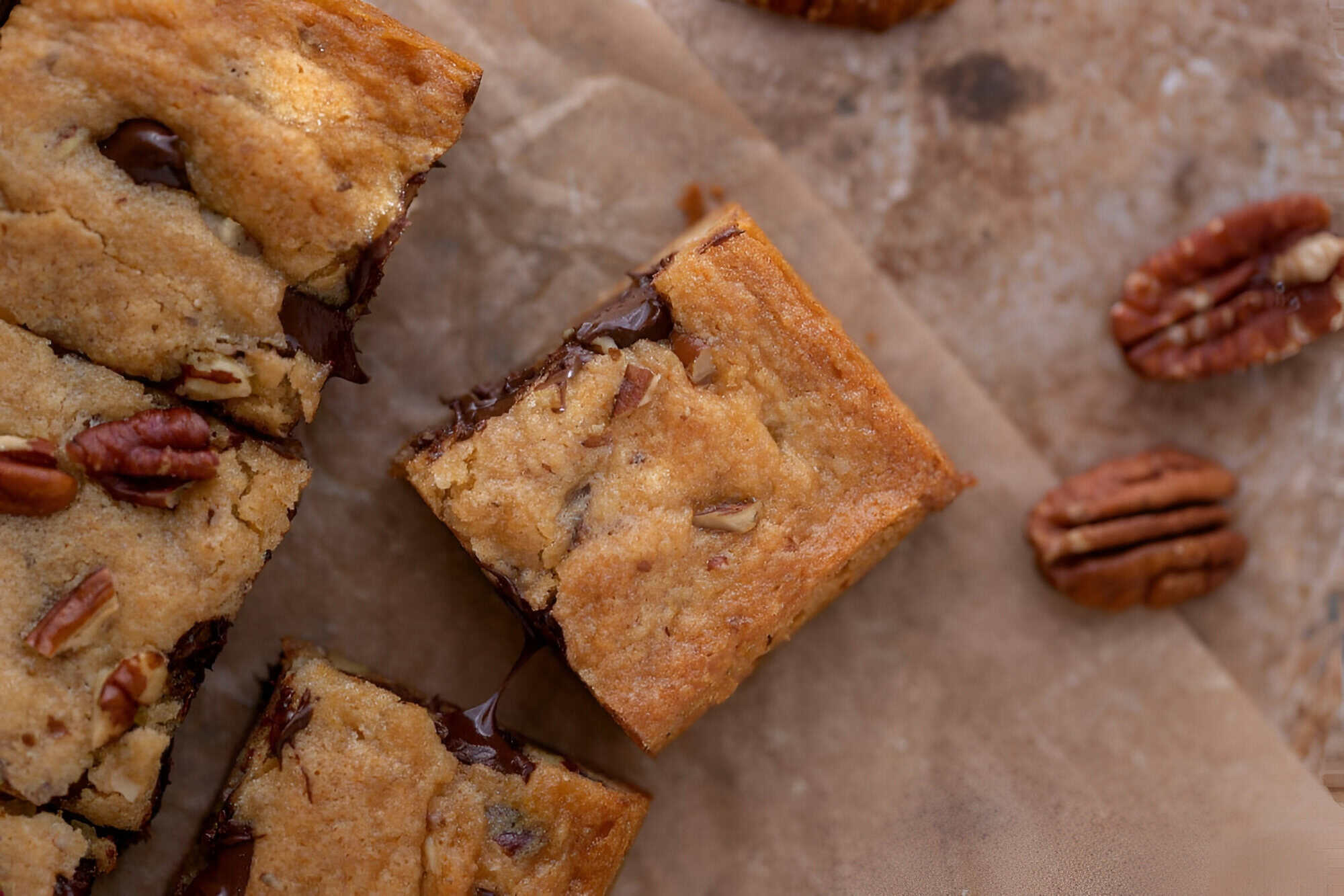 Chewy chocolate chip pecan blondies cut into squares and stacked on parchment paper.