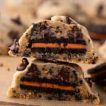 A Halloween Oreo stuffed chocolate chip cookie cut in half stacked on top of each other.