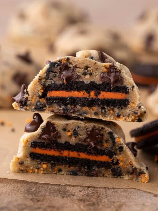 A Halloween Oreo stuffed chocolate chip cookie cut in half stacked on top of each other.