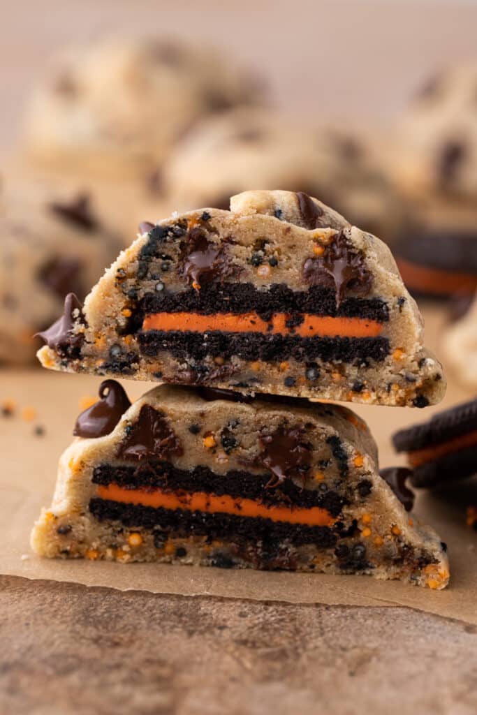 A Halloween Oreo stuffed chocolate chip cookie cut in half stacked on top of each other. 