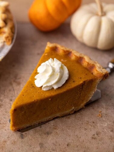 slice of pie on a spatula that's on a table from the recipe for two pumpkin pies