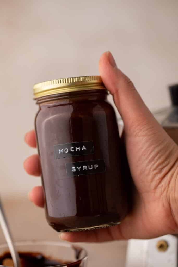 jar of mocha coffee syrup being held up by a hand