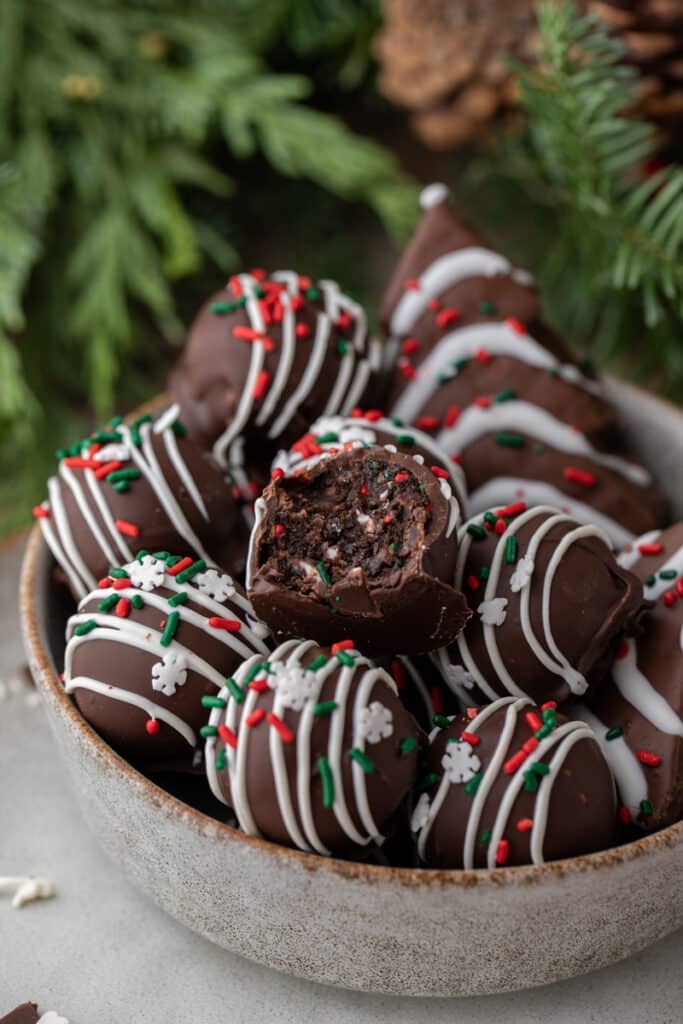 multiple Little Debbie Chocolate Christmas tree cakes truffles in a bowl with one that is split in half on top